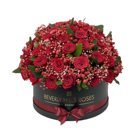 Red roses in Flame flower box with red hypericum berries, red gypsophila and foliage