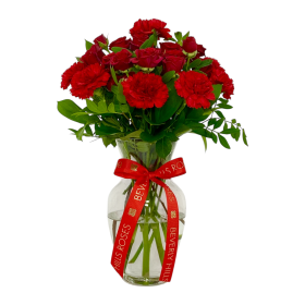 Red roses and red carnations in a glass vase with greenery in Dubai