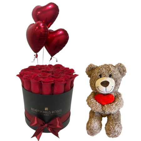 Brown teddy bear holding a red heart with 22 fresh red roses and three red heart-shaped balloons – Valentine’s Day gift bundle in Dubai